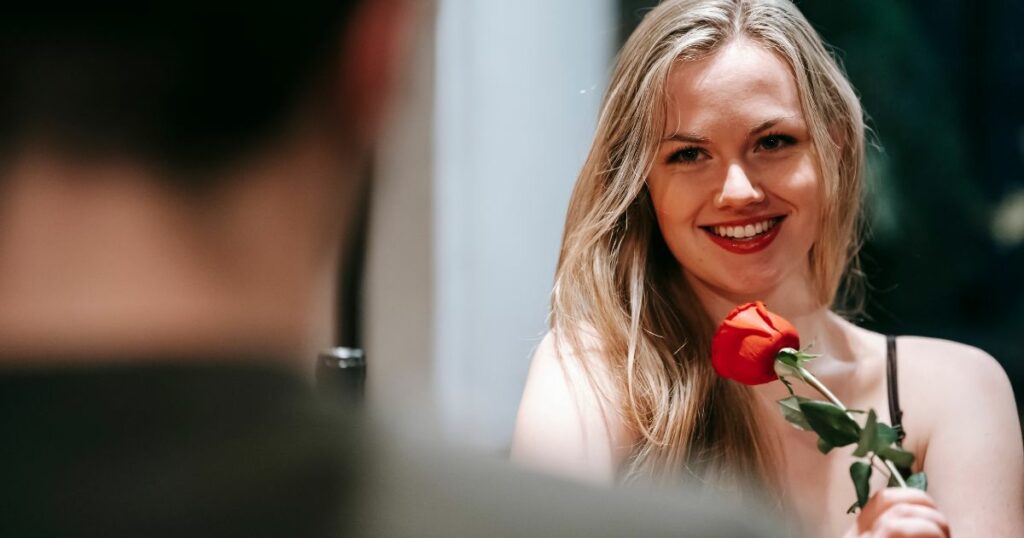 A woman smiling while holding a rose