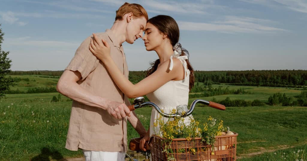 A couple touching faces infront of a bicycle