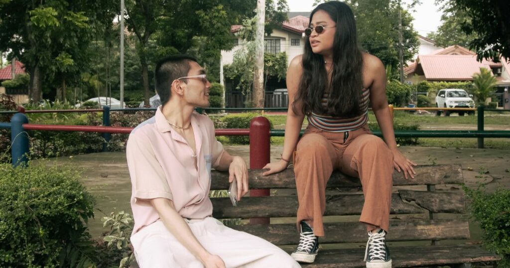 A man and woman talking on a bench in a park