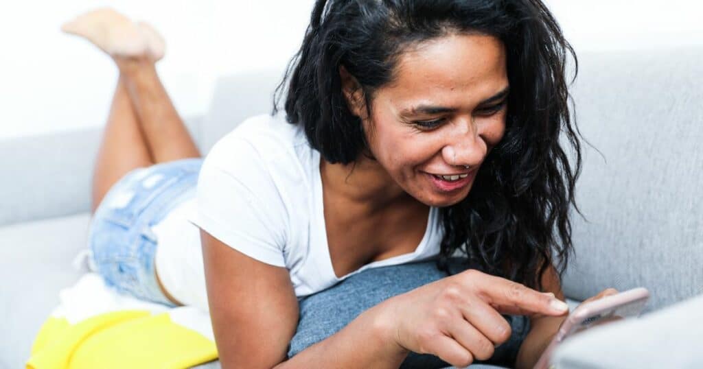 A woman smiling at her phone 